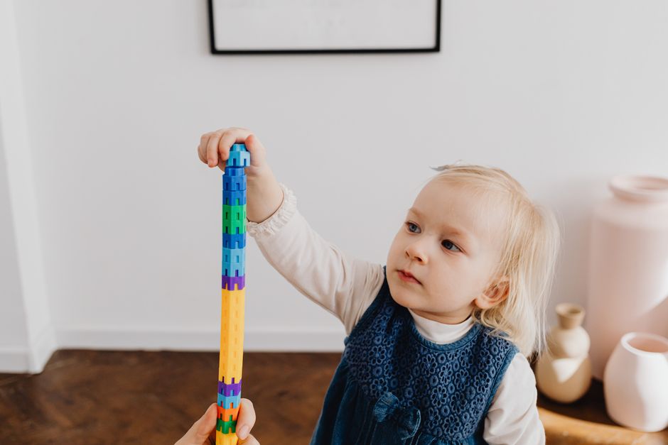 Cute toddler stacking colorful blocks at home, developing motor skills.